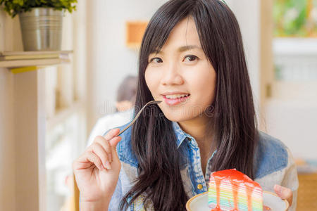 美丽微笑的年轻亚洲女人吃蛋糕