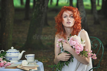 美丽的红头发女人摆着花