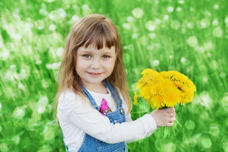特写情感肖像可爱的小女孩与蒲公英花束站在绿色的草地上