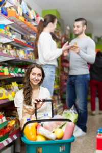 顾客站在货架附近，商店里有罐头食品