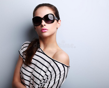 美丽的年轻女子，穿着时尚的太阳眼镜，摆着姿势和腰部