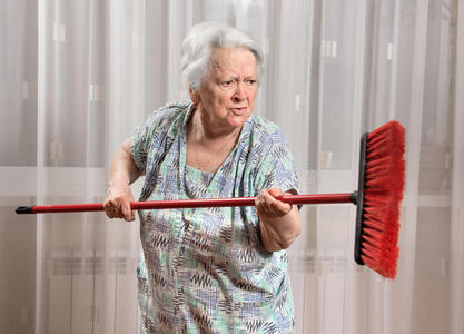 愤怒的老妇人用扫帚威胁
