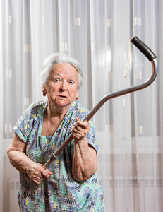 愤怒的老妇人用拐杖威胁