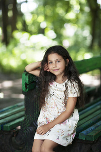美丽的女孩笑着坐在公园的长凳上