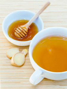 木制背景上有蜂蜜的一杯姜茶。