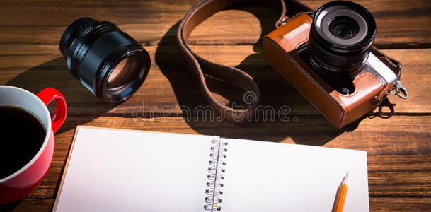 在咖啡杯和照相机旁边的记事本上的一支笔