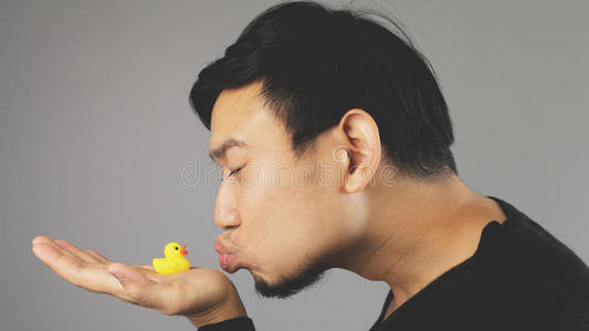 一个有趣的家伙亲吻他的橡胶鸭子。