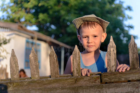可爱的男孩在木栅栏对着相机微笑