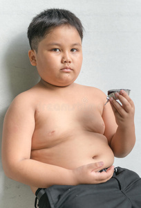可爱的胖男孩,灰色背景上有巧克力蛋糕.照片