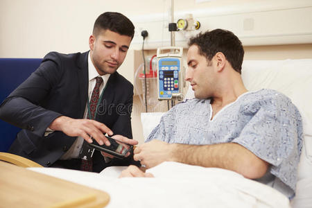 医生坐在男性病人的床上使用数码片