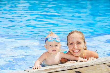 有趣的小男孩和妈妈在游泳池游泳的肖像
