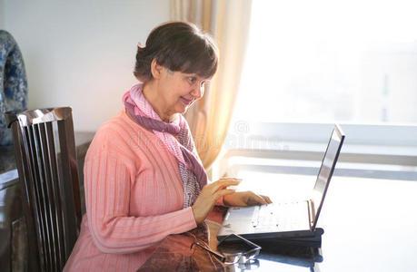 年长的漂亮女人在笔记本电脑上工作