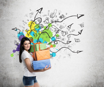 一个黑发女人拿着三个五颜六色的礼品盒。 用箭头和购物图标在墙上画草图。