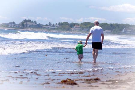 祖父和他的孙子在海滩上散步