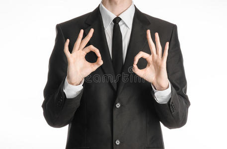 商人和手势主题一个穿着黑色西装，打着领带的人，在斯图的白色背景上显示出两只手的OK标志