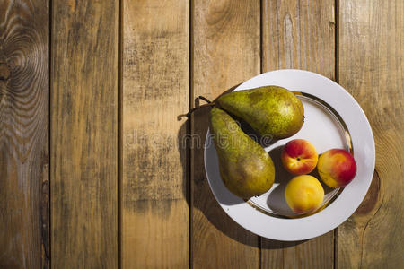 水果躺在盘子里，站在木制的背景上。