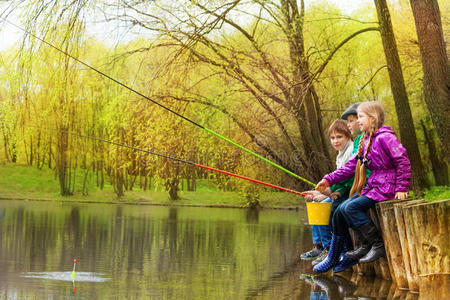 孩子们一起坐在池塘边钓鱼
