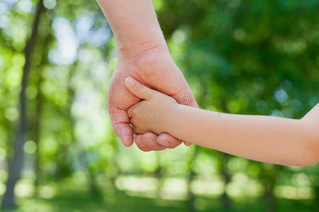 在美丽的波基背景下,幸福的家庭观念老手牵小手父亲牵着孩子的手,在