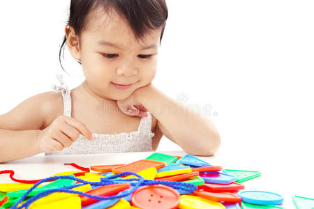 特写亚洲女婴玩线按钮线玩具隔离在白色背景。