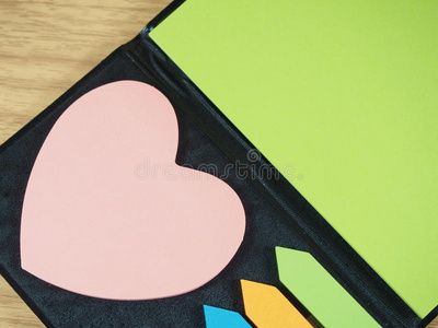 彩色粘纸，粉红色心形，箭头形状在黑色笔记本上