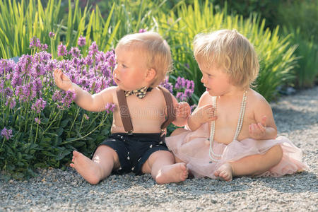 坐在美丽花园里看花的小女孩和小男孩