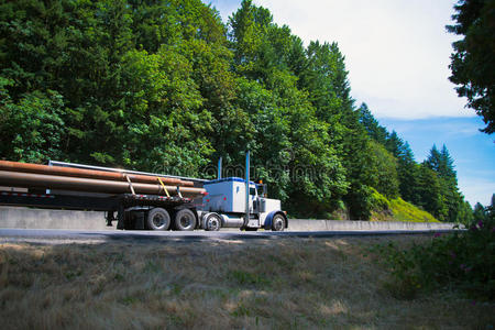 大型钻机半卡车驾驶公路在平床上携带长管