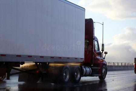 白天驾驶室半卡车拖车在雨和阳光反射