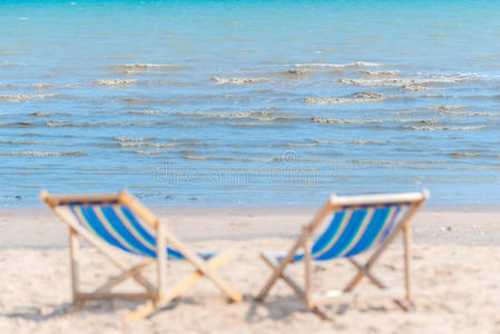 阳光明媚的一天，沙滩上的椅子散落在沙滩上寻找