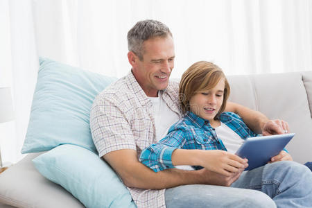 父亲和儿子在沙发上用笔记本电脑放松