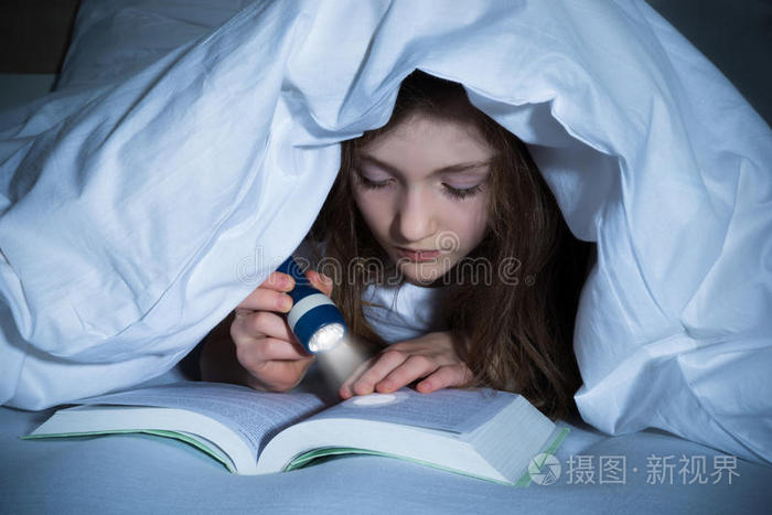 女孩用手电筒看书