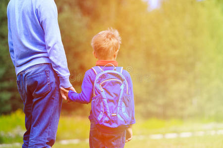 父亲用背包牵着小儿子的手照片