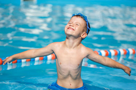 无忧无虑的小男孩在游泳池里张开双臂照片