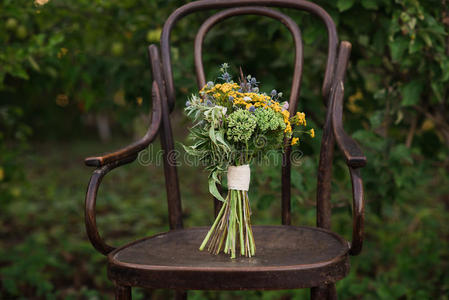美丽的婚礼花束在一把老式的椅子上，在夕阳的光线下，装饰着大自然，为婚礼做准备