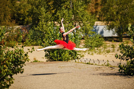 芭蕾舞演员穿着红色的芭蕾舞裙在公园跳舞。 宏伟的PASDES聊天