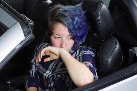 沮丧的十几岁女孩坐在汽车的驾驶座上
