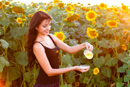 漂亮的女孩从水罐里倒葵花油照片