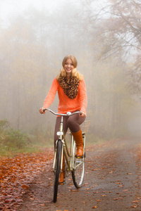 女孩在秋天的公园里骑自行车放松