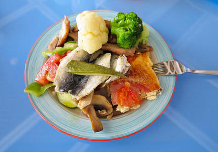蓝色桌子上盘子里的鱼和蔬菜