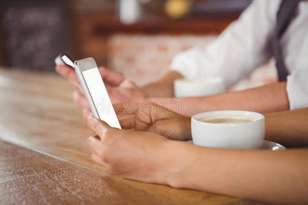 一对可爱的情侣坐在咖啡馆里看着智能手机
