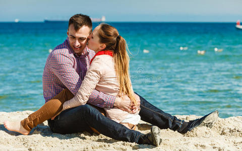 一对夫妇坐在海滩上放松和拥抱