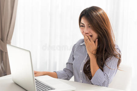 美丽的年轻亚洲妇女在家里的客厅里使用笔记本电脑