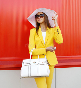 时尚优雅的女人穿着黄色西装衣服，草帽