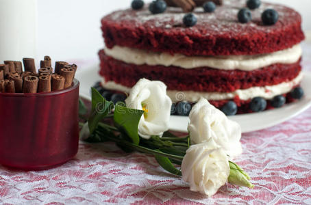 一个美丽的自制蛋糕在花边表面装饰精致的奶油花，蓝莓和肉桂棒