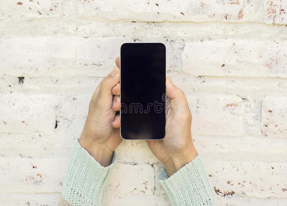 女孩拿着手机在砖墙背景上
