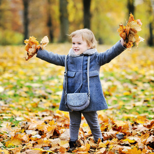 小女孩在秋园里抛树叶