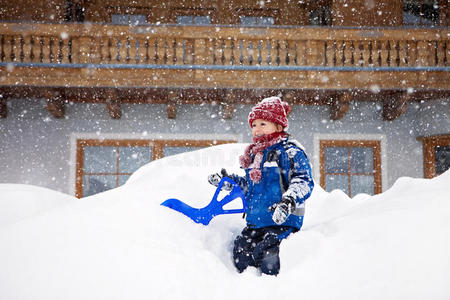 穿着蓝色冬装的可爱小男孩，在雪地里户外玩耍