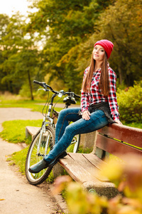 在秋天的公园里骑着自行车放松的女孩。