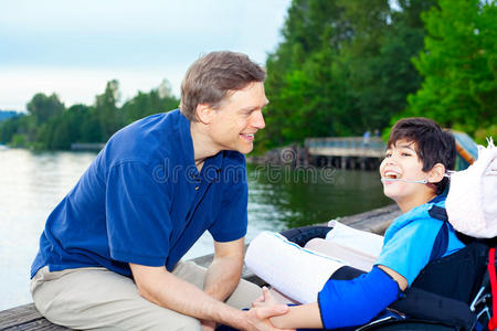 父亲在湖边和轮椅上的残疾儿子交谈