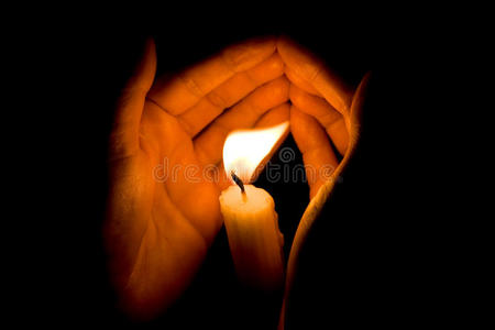 双手捧蜡烛祈祷双手在黑暗中保护明亮的烛光.照片