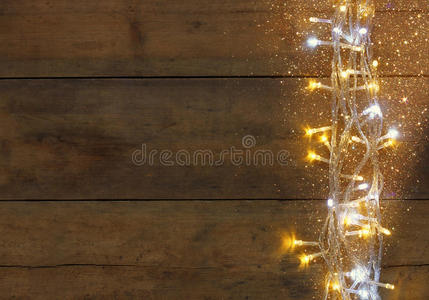 圣诞节温暖的金色花环灯在木制乡村背景上。 过滤图像与闪光覆盖。